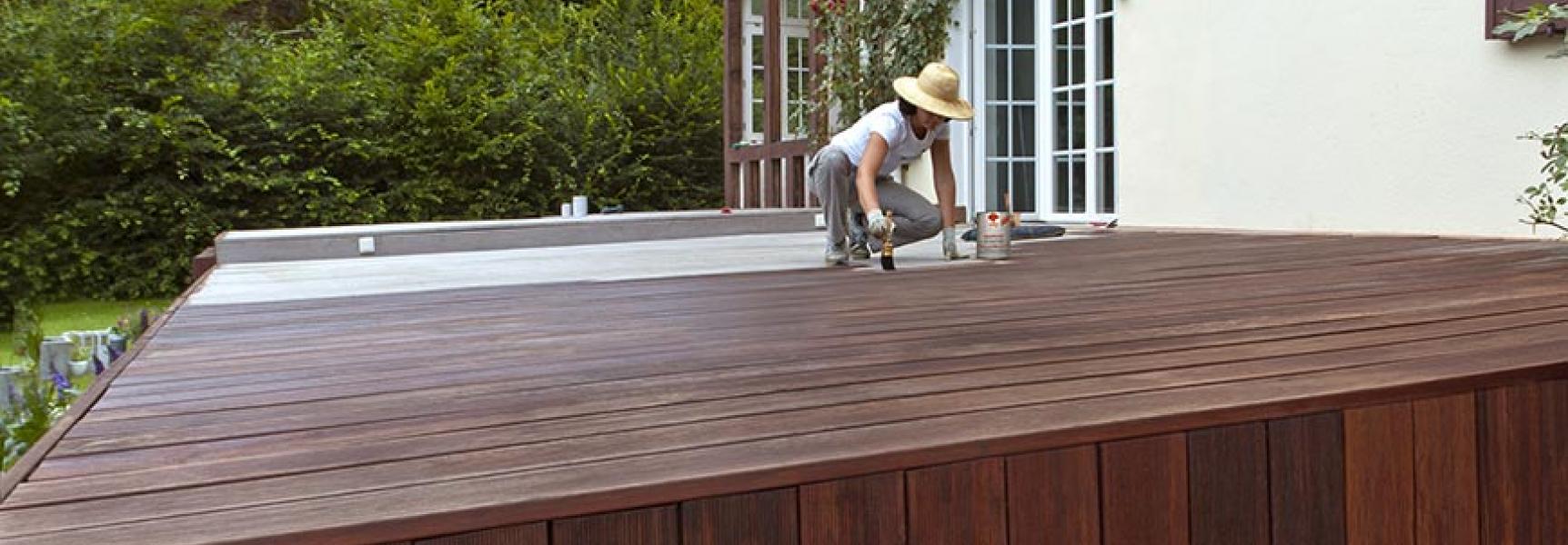 Frau streicht Terrasse mit Naturholzöl