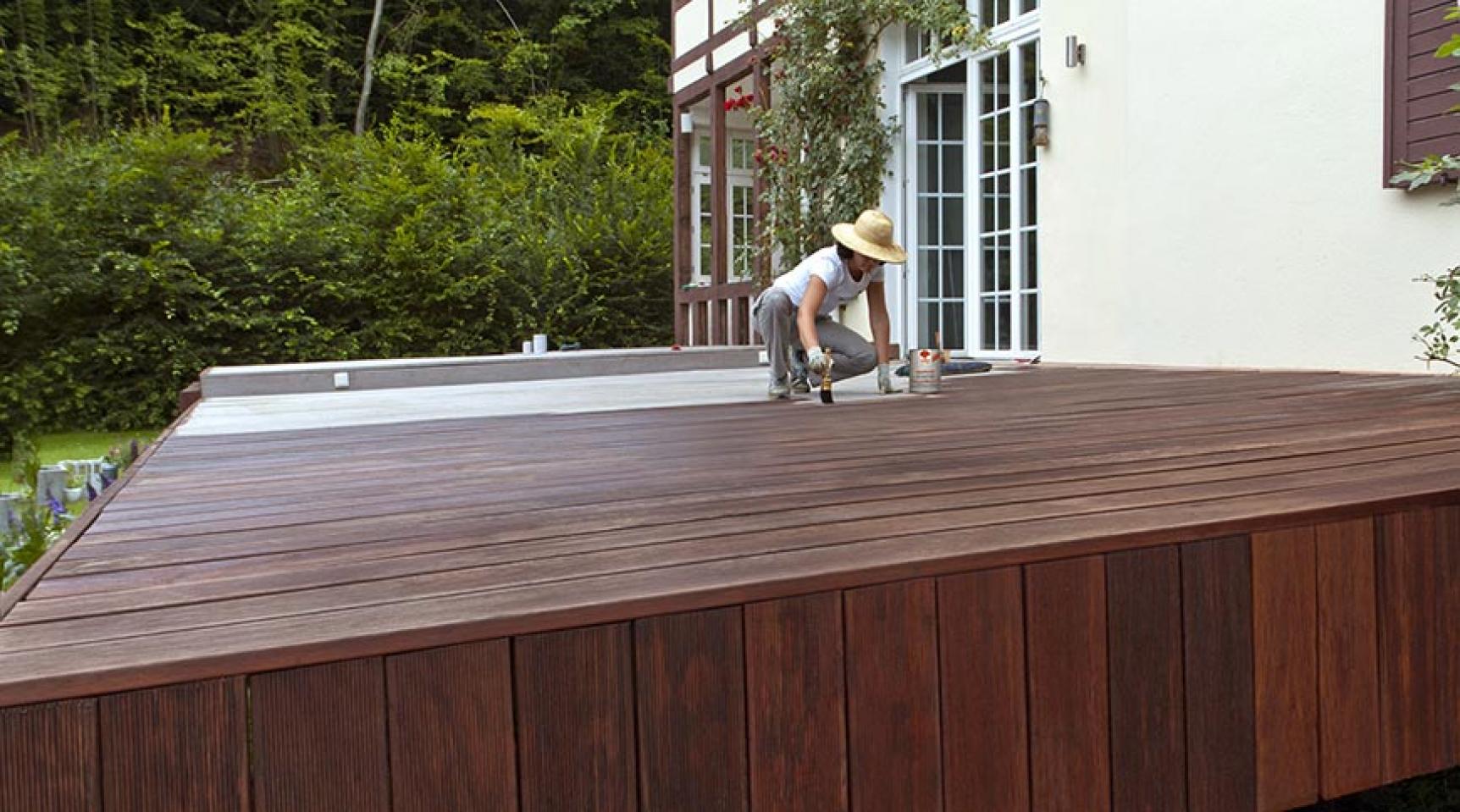 Frau streicht Terrasse mit Naturholzöl