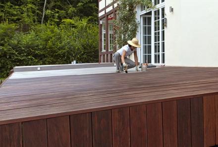 Frau streicht Terrasse mit Naturholzöl